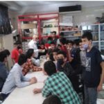 دانش‌آموزان در حال شرکت در یک فعالیت آزمایشگاهی گروهی تحت نظارت معلم و معاون آموزشی مدرسه