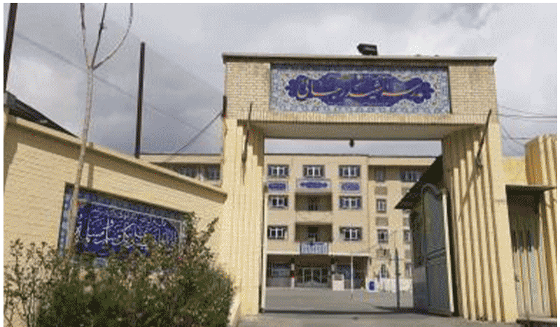 نمای ورودی ساختمان مدرسه با درب فلزی، تابلو فارسی و معماری آجری‌فیروزه‌ای