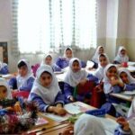 دانش‌آموزان دختری با روسری نشسته در کلاس درس که در حال فعالیت‌های یادگیری هستند