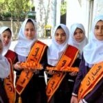گروهی از دانش‌آموزان دختری در حال برگزاری مسابقه حدث که نوارهای نارنجی و قرمز در دست دارند