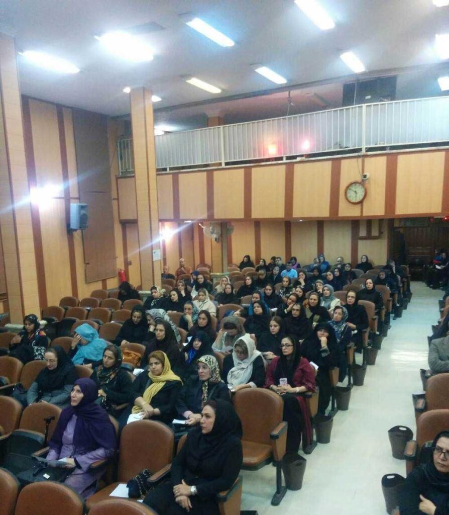 جلسهٔ جمعی اولیا و مربیان در سالن تالار مدرسهٔ سیمایِ نور، با حضور تعدادی زیادی از شرکت‌کنندگان نشسته بر صندلی‌های قهوه‌ای