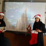دو دانش‌آموز دختر با پوشش کریسمسی و کلاه بابانوئل، جلوی صفحه‌نمایش قلعه‌ای