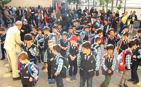 تجمع دسته‌جمعی دانش‌آموزان در حیاط مدرسه برای یک مراسم رسمی صبح، با حضور معلمان و مسئولین