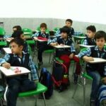 دانش‌آموزانی در حال فعالیت و درس خواندن در کلاسی با صندلی‌های سبز رنگ و میز‌های متصل