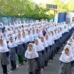 گروه بزرگی از دانش‌آموزان دختر با لباس فرم دانشگاهی در حیاط مدرسه، احتمالاً در حین مراسمی یا رویداد دسته‌جمعی