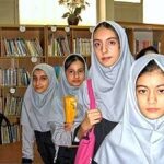 گروهی از دانش‌آموزان پوشیده‌سر در حال تصویربرداری در کتابخانه مدرسه کنار قفسه‌های کتاب