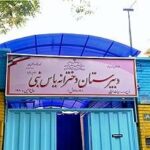 نمای بیرونی ساختمان مدرسه یاسنابی با درب آبی، تابلوی فارسی دائمی و دیوارهای رنگی