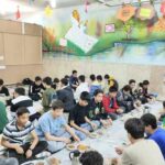 دانش‌آموزان در حال شرکت در یک مراسم غذایی دسته‌جمعی در کلاس درس با حضور معلم