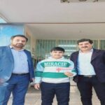 معاونان و مسئولان مدرسه در حال تقدیر و اهدای بنر سبز میراسل به دانش‌آموز در حیاط داخلی مدرسه