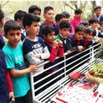 دستهای از دانشآموزان مدرسهای در حیاط و فضای باز مشغول یک فعالیت آموزشی تعاونی با استفاده از سطح رسم و نوشتاری
