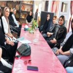 گروهی از دختران دانشآموز نشسته دور میز صورتی در یک جلسه یا برنامه آموزشی تفاعلی