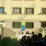 نمایی از حیاط مدرسه با دیدِ ساختمان اصلی و دانش‌آموزانی نشسته