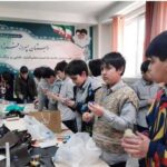 دانش‌آموزان در حال انجام یک فعالیت دستی و پروژه‌ی گروهی در کلاس درس، به دور میز و با مصالح و ابزارهای مختلف