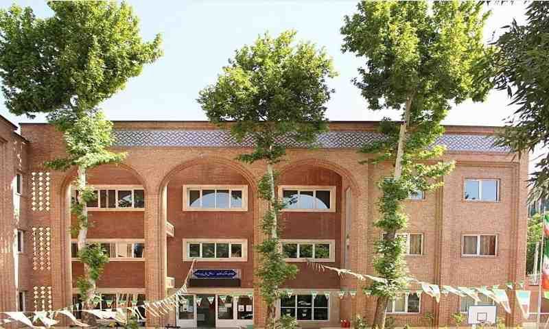 نمای بیرونی ساختمان اصلی مدرسه با معماری خشتی، پنجره‌های متعدد و فضای سبز