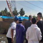 گروهی از دانش‌آموزان در حال شرکت در یک کارگاه/پروژه عملی ساختمانی با پوشش ایمنی و کلاه‌های محافظ در محل کارگاه
