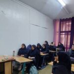 دانش‌آموزان دختری در کلاس درس حین درس‌خوانی گروهی با حضور معلم
