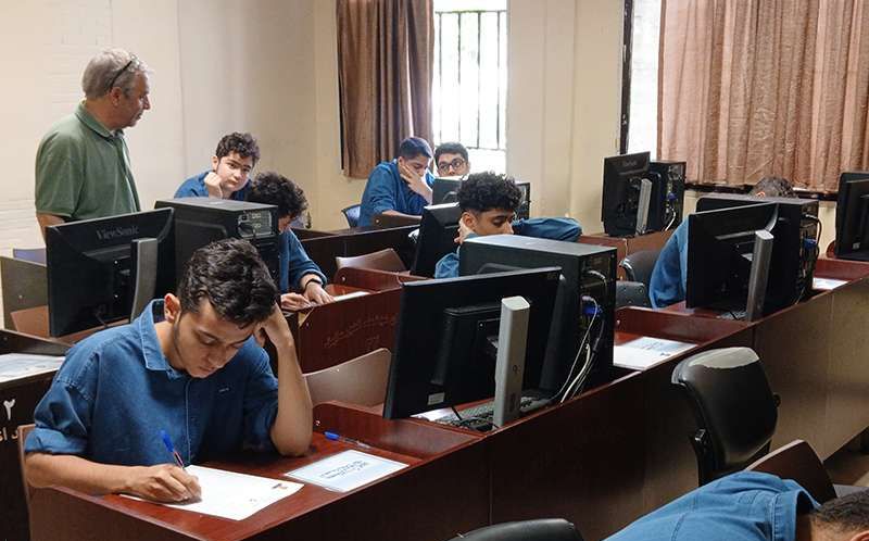 دانش‌آموزان در حال کار بر روی رایانه‌های فردی با تحت نظارت معلم در سایت کامپیوتر مدرسه