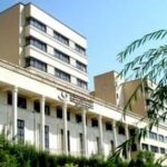 نمای خارجی ساختمان مدرسه با معماری سنتی، دارای نما‌های درپوش سفید رنگ، پنجره‌های منظم و درختان سبز، نمایندگی از معماری آموزشی
