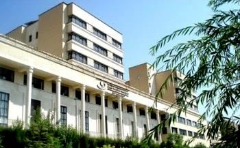 نمای خارجی ساختمان مدرسه با معماری سنتی، دارای نما‌های درپوش سفید رنگ، پنجره‌های منظم و درختان سبز، نمایندگی از معماری آموزشی