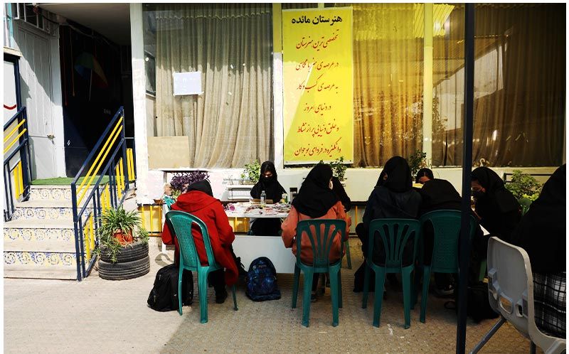 گروهی از دانش‌آموزان در حال شرکت در یک کارگاه یا جلسه آموزشی گروهی در فضای نیمه‌داخلی مدرسه
