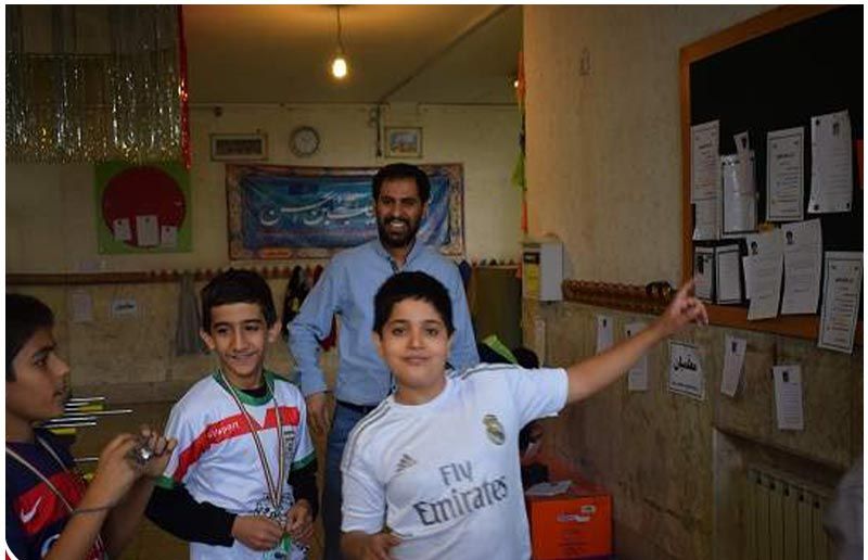معلم و دانش‌آموزان در حال تجلیل و عکس یادگاری با مدال برنده در کلاس درس