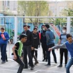 دانش‌آموزان در حین شرکت در یک فعالیت ورزشی گروهی و تمرین در حیاط مدرسه
