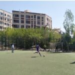 دانش‌آموزان در حال بازی فوتبال در حیاط مدرسه در یک روز آفتابی