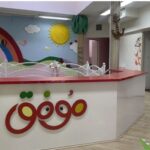 اتاق کلاس درس مدرسه با تزئینات رنگین شامل نقاشی دیواری با رنگین‌کمان، خورشید، ابرها و دکوراسیون جانوری