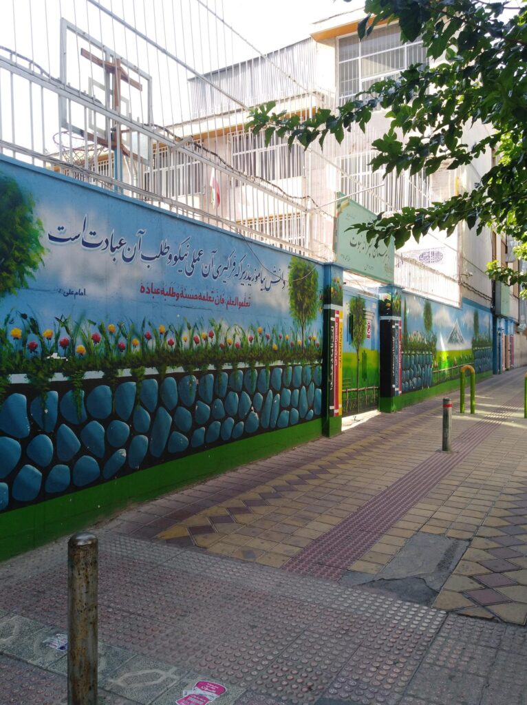 دیوار نقاشی‌شده و حلقه بسکتبال حیاط مدرسه نبوت در هفت‌حوض تهران