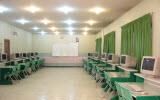 کلاس درسی خالی با دیوارهای سبز، صندلی‌های سبز و نورپردازی LED سقفی برای آموزش دانش‌آموزان