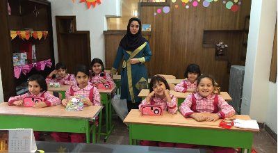 گروهی از کودکان دختر در حال انجام فعالیت صنایع دستی و کار گروهی در کلاس درس زیر راهنمایی معلم
