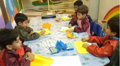 دانش‌آموزانی در حال انجام فعالیت هنری و نقاشی در کلاس، با استفاده از رنگ‌ها و مواد خلاقانه روی کاغذ