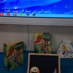 گوشه‌ای از کلاس با تخته هوشمند، تخته آموزشی کوچک و کتاب‌های داستان در مدرسه ستارگان زمین