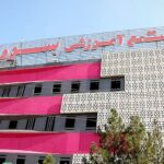 نمای خارجی ساختمان مدرسه با معماری مدرن، رنگ‌های صورتی و سفید، پنجره‌های منظم و تزیینات هندسی سفید رنگ