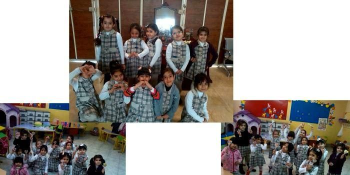 گروهی از دانش‌آموزان مدرسه با لباس‌های مدرسه ایستاده برای یک عکس جماعی؛ در پس‌زمینه تزئینات و پوسترهای کلاس درسی دیده می‌شود